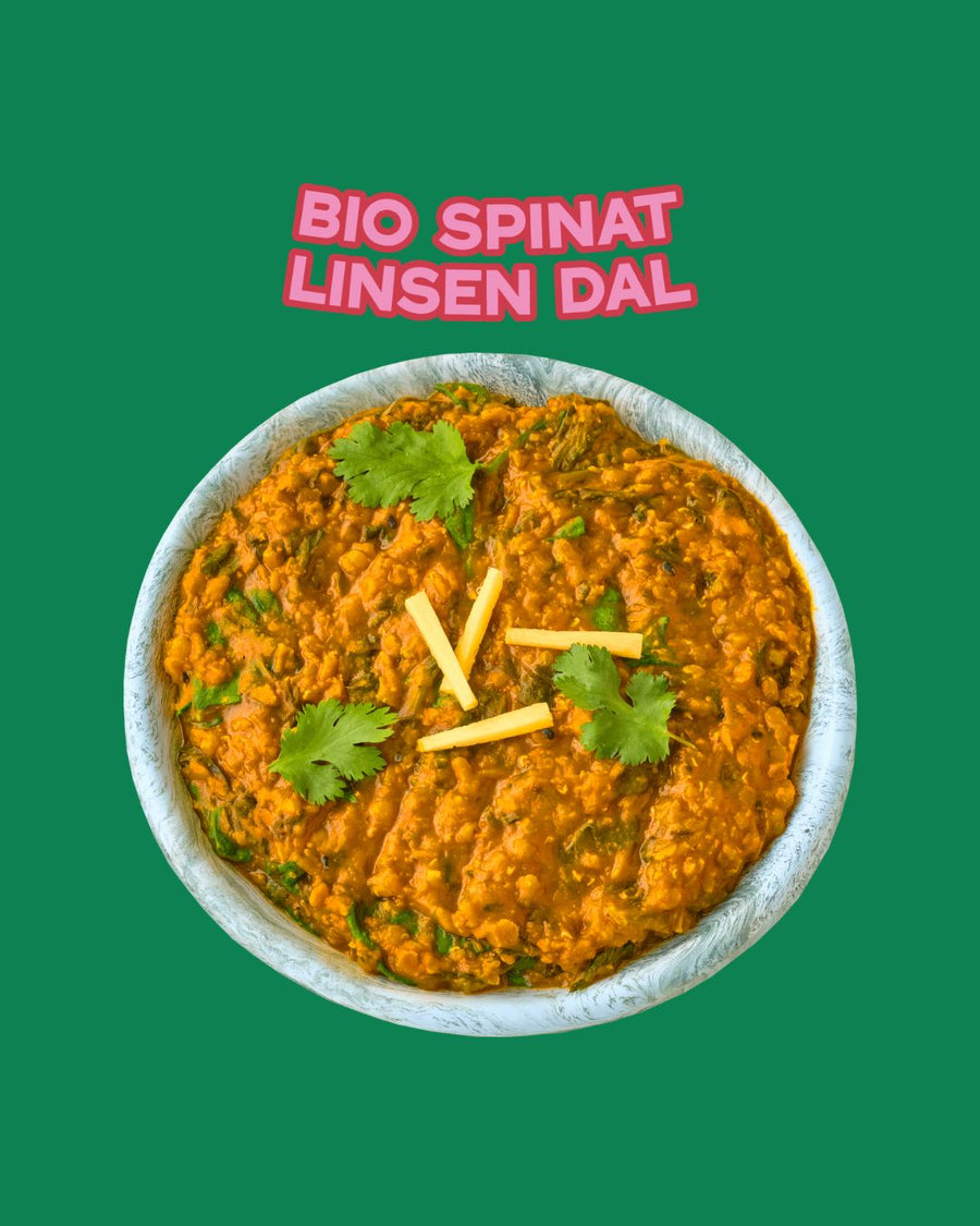 Serviertes Bio Spinat Linsen Dal von Karma Food, dekoriert mit Koriander und Ingwerstreifen auf grünem Hintergrund
