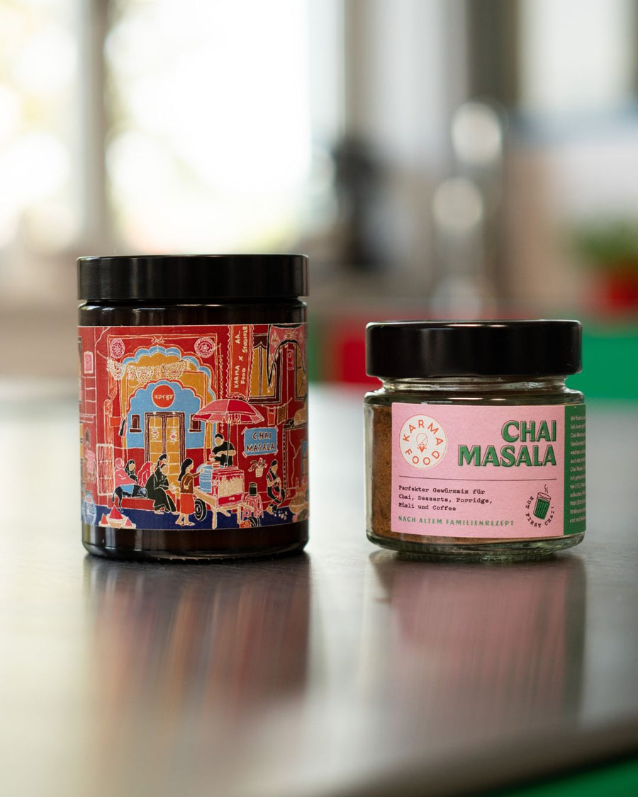 Karma Food Chai-Duftkerze mit Pink-Monkey-Design neben einem Glas Chai Masala Gewürzmix – beide Produkte auf Küchentresen mit unscharfem Hintergrund